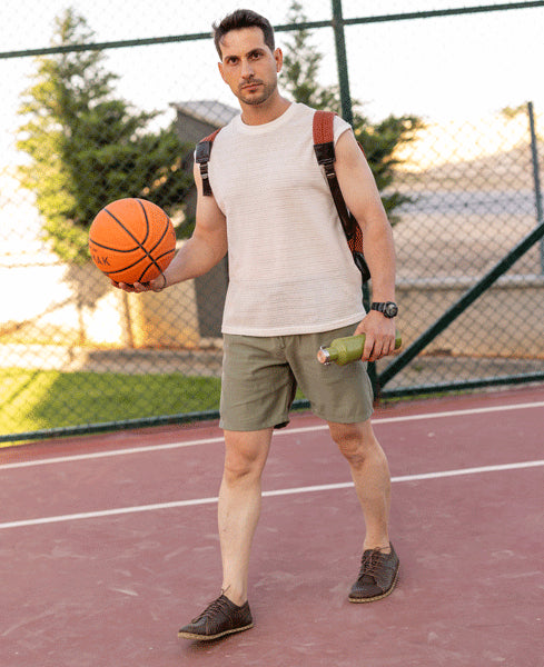 Man holding a basketball and a bottle on a basketball court