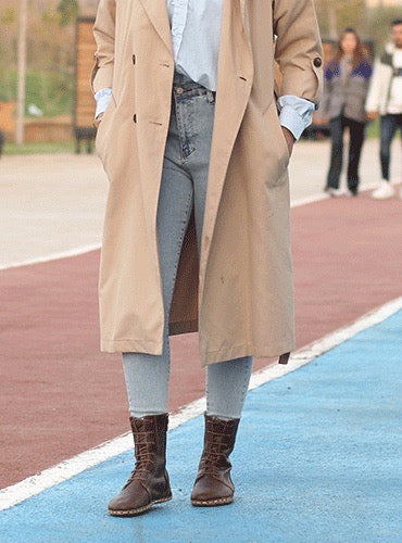 Person wearing a beige trench coat and brown boots on a track