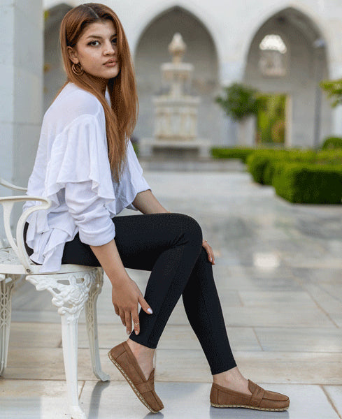 Woman sitting on a chair in an outdoor setting with a fountain in the background